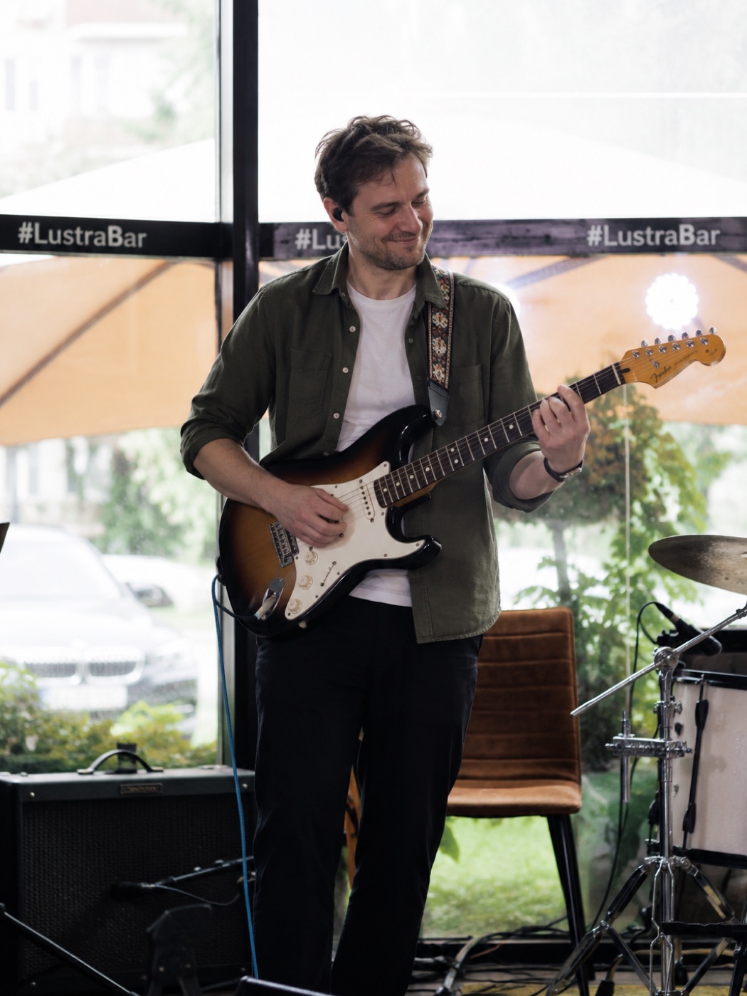 Взрослый ученик школы играет на электрогитаре Fender на сцене